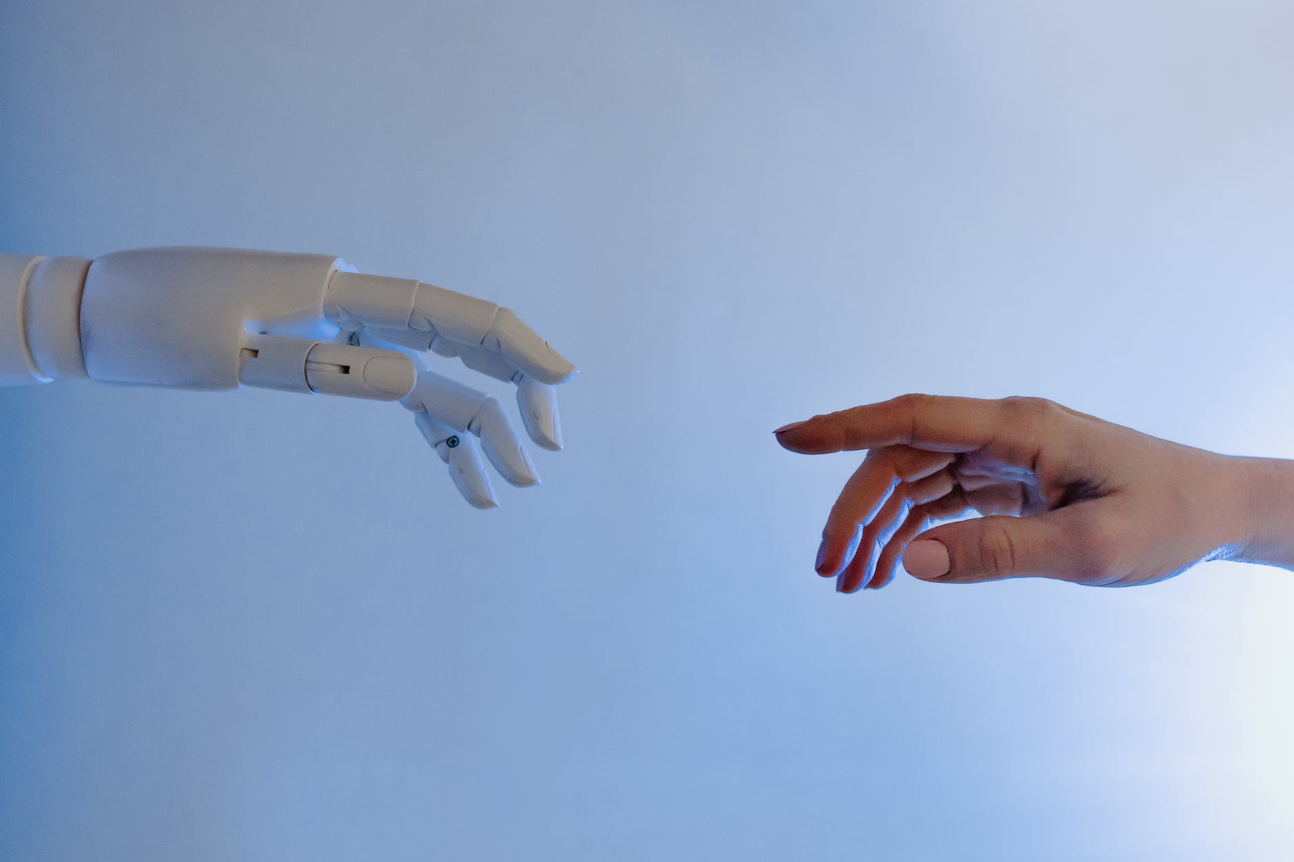 A human and robotic hand reaching towards each other.