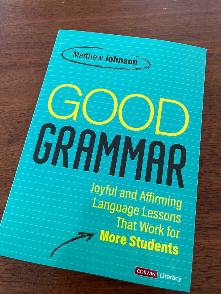 A close-up view of the book titled 'Good Grammar' by Matthew Johnson, featuring a bright turquoise cover with bold yellow and black lettering, placed on a wooden surface.