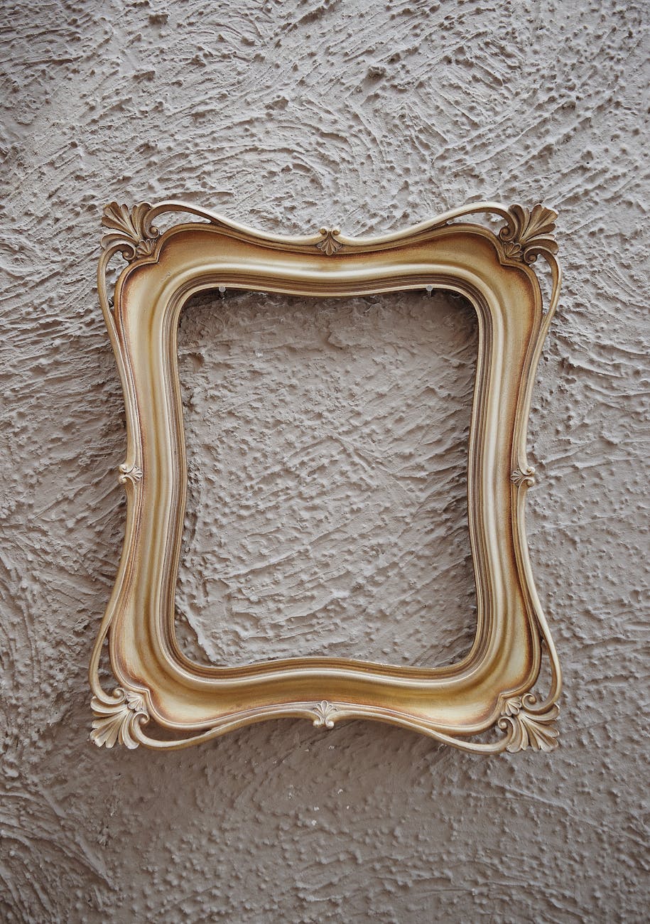 A decorative golden picture frame against a textured beige wall.